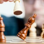 Close-up of a chess game with a focused player, emphasizing strategy and competition.