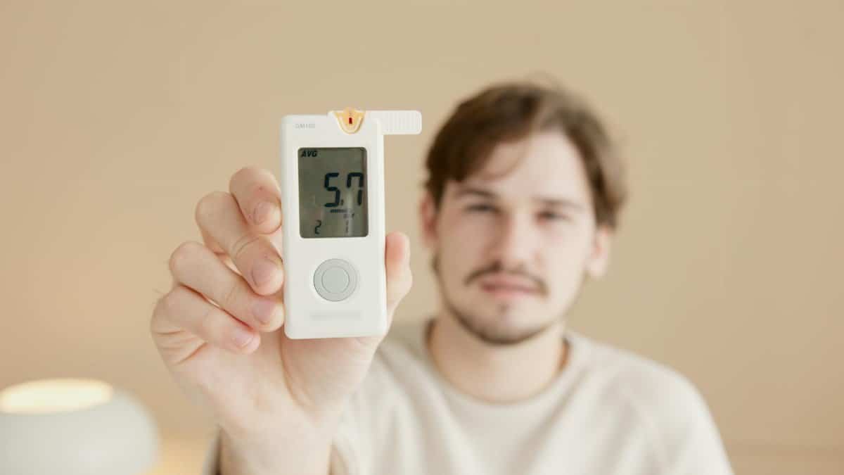Close-up of a man holding a glucometer to check blood sugar levels, highlighting diabetes awareness.