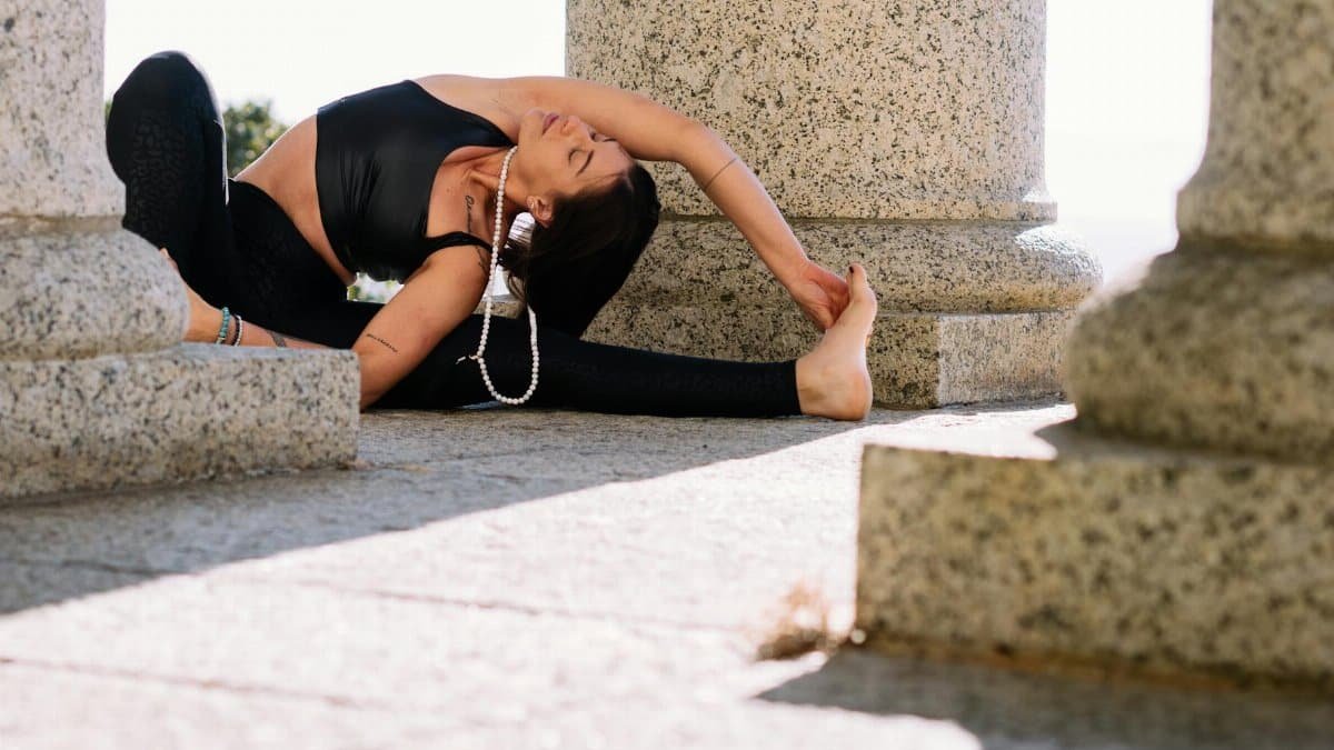 Woman practicing yoga in an outdoor stone setting, radiating serenity.