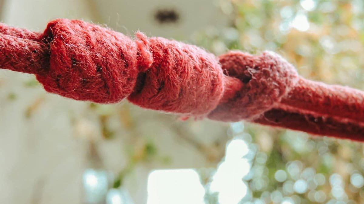 Detailed close-up of red rope with knots against a bokeh background, highlighting texture and focus.