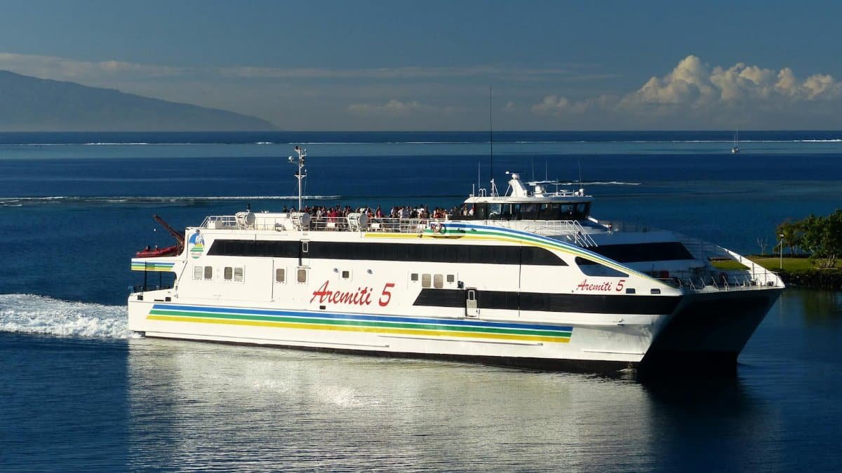 A large passenger ferry sails through calm ocean waters under a clear blue sky.