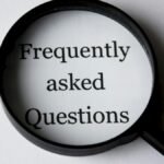 Close-up of a magnifying glass focusing on the phrase 'Frequently Asked Questions'.