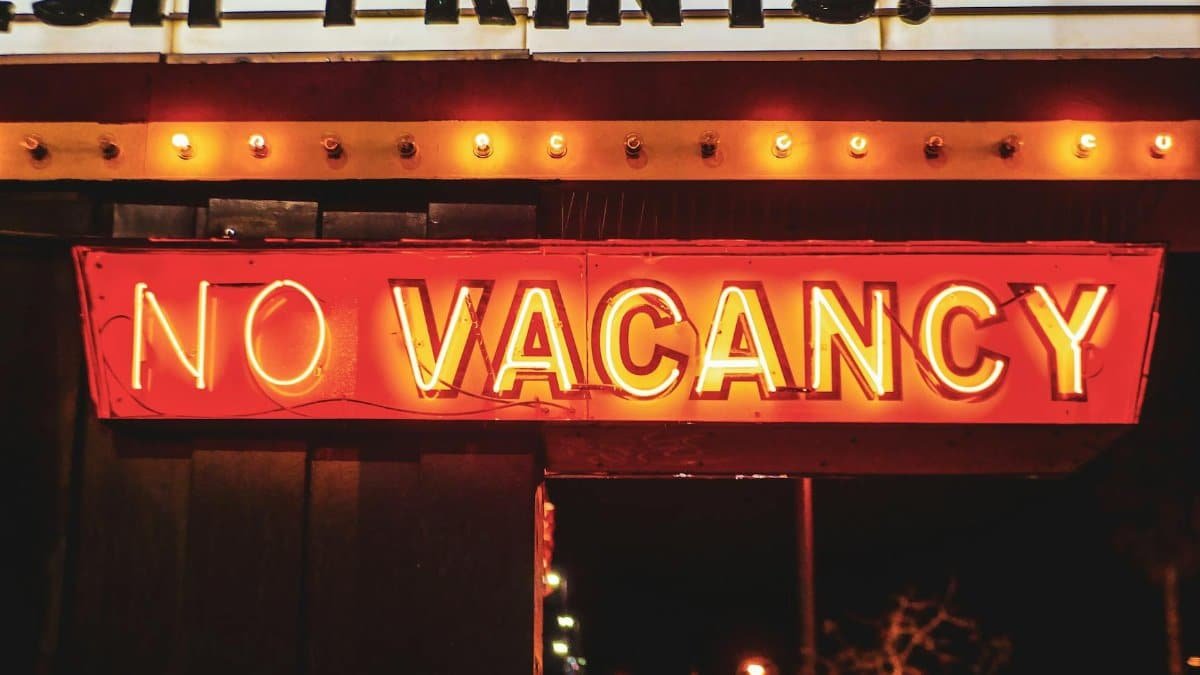 Bright neon 'No Vacancy' sign glowing at night, evoking urban nightlife vibrance.