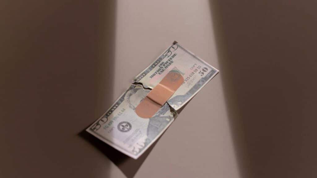 A $50 bill with a bandage symbolizes financial recovery and repair.