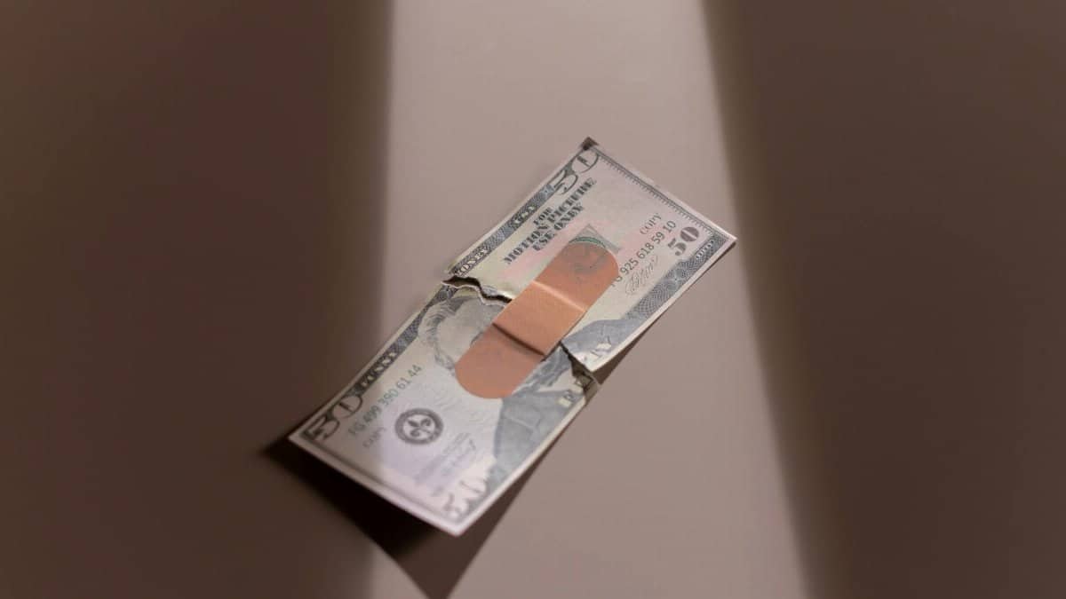 A $50 bill with a bandage symbolizes financial recovery and repair.