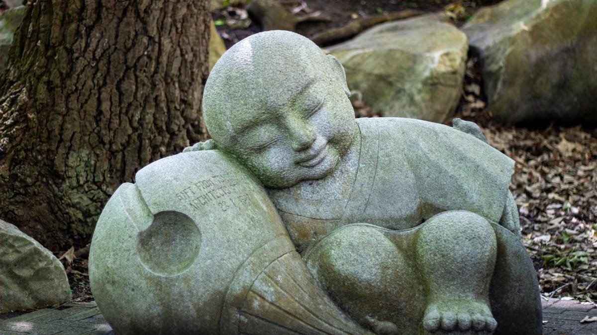A peaceful Buddha statue nestled among rocks and trees in Darling Harbour, Australia.