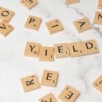 Scrabble tiles forming the word 'YIELD' on a marble surface, symbolizing finance and investment.