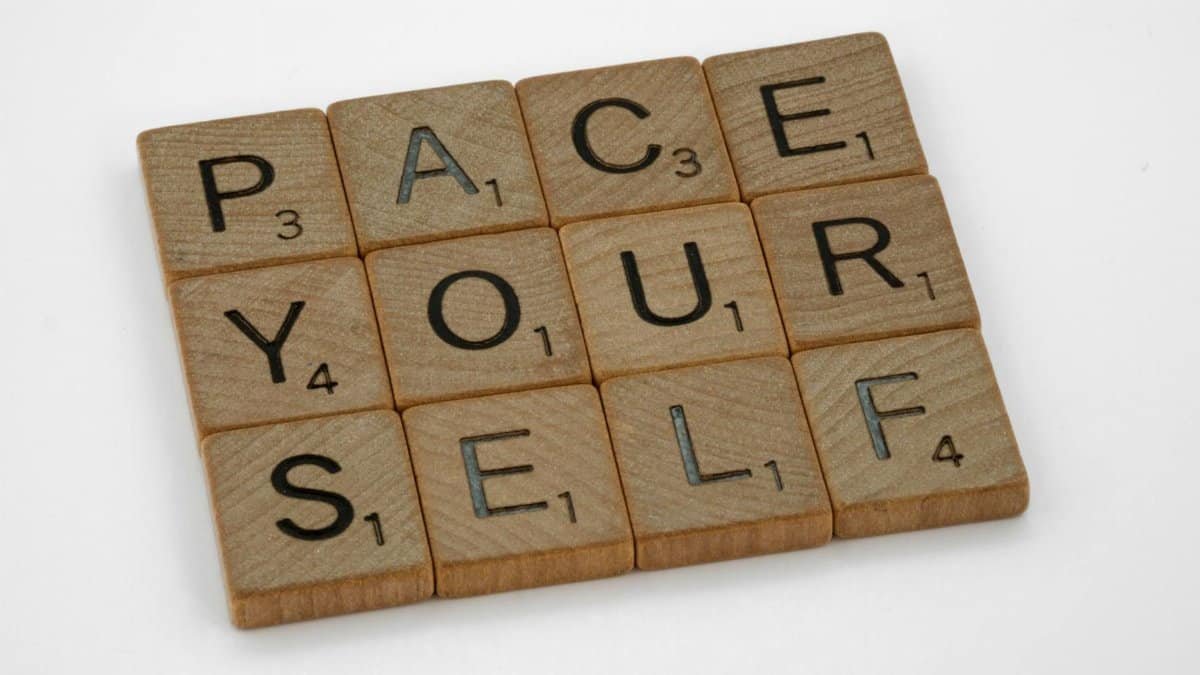 Scrabble tiles forming the phrase 'Pace Yourself' on a gray surface, conveying a motivational message.