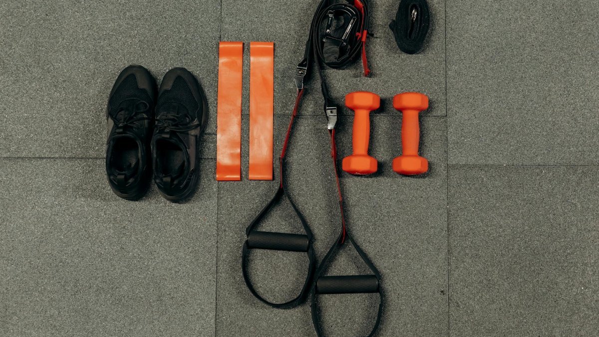 Flat lay of fitness gear including dumbbells, sneakers, and resistance bands for a home workout.