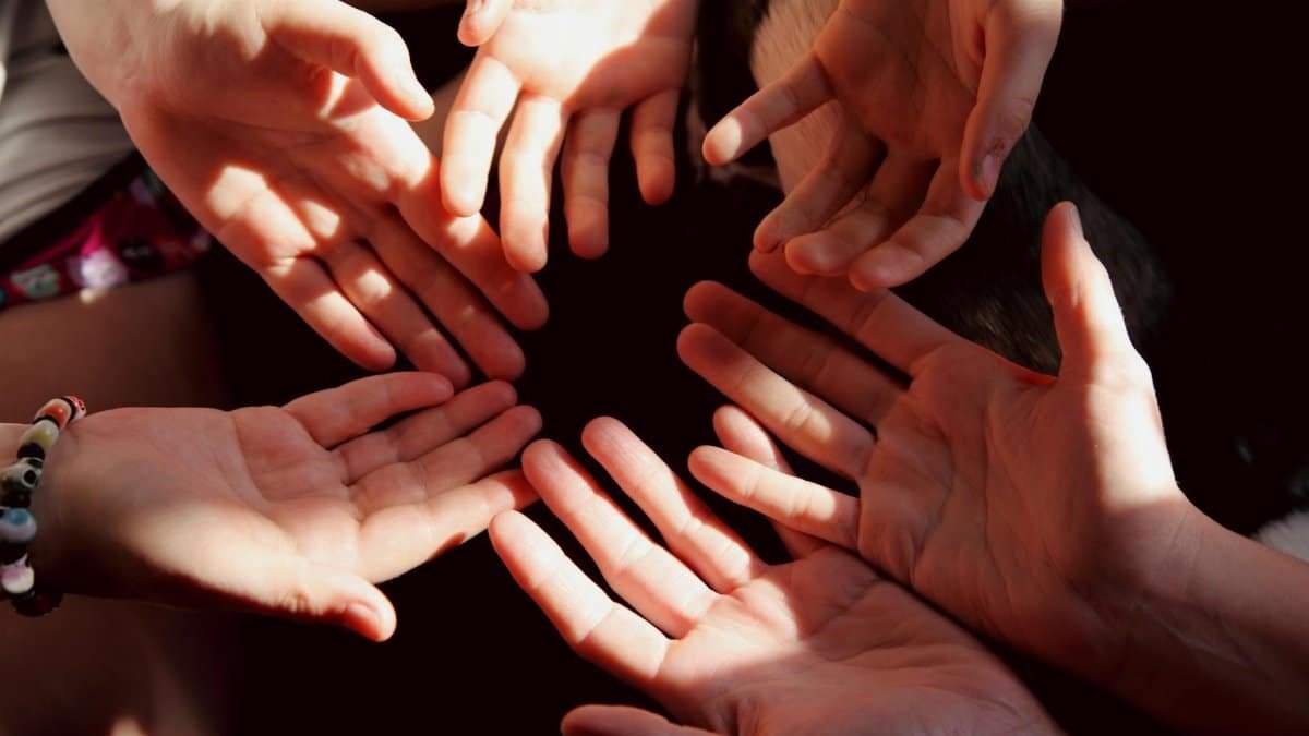 A close-up of diverse hands in a circle symbolizes unity and teamwork.