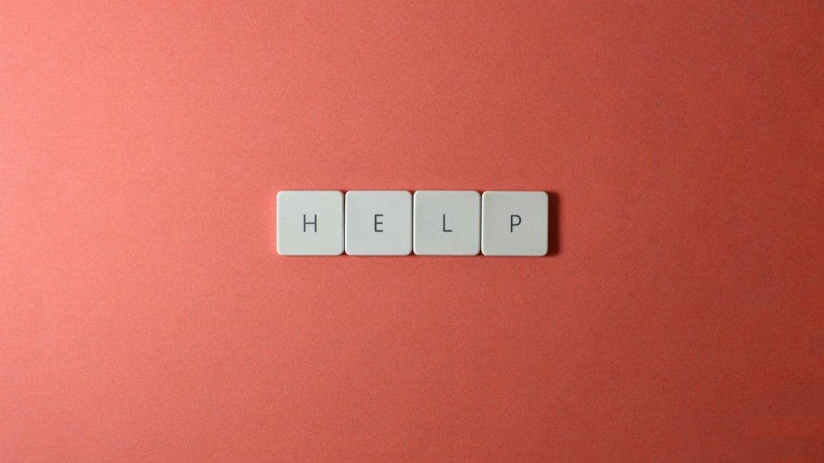 Creative layout of keyboard tiles spelling 'Help' on a red background, offering copyspace.