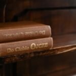 A cozy rustic wooden shelf displaying vintage books with gold embossed titles.