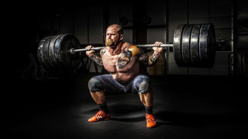 Muscular man lifting heavy weights during an intense squat session inside a gym.