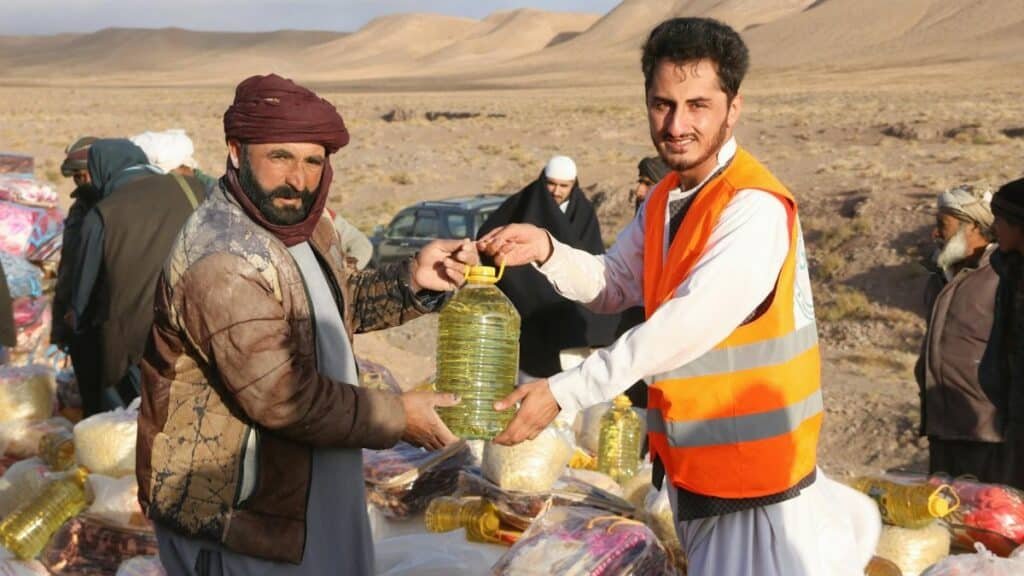 Community members receive supplies during a humanitarian aid distribution in a desert village.