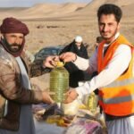 Community members receive supplies during a humanitarian aid distribution in a desert village.