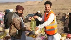 Community members receive supplies during a humanitarian aid distribution in a desert village.