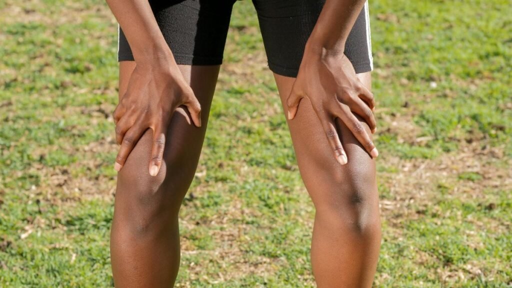 Close-up of an athlete resting after a workout, grasping knees outdoors.