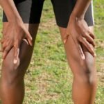 Close-up of an athlete resting after a workout, grasping knees outdoors.