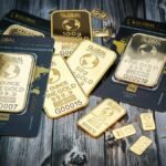 A collection of fine gold bars displayed on a textured wooden surface.