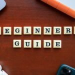 Creative flat lay of gadgets and 'Beginners Guide' text on wooden table.
