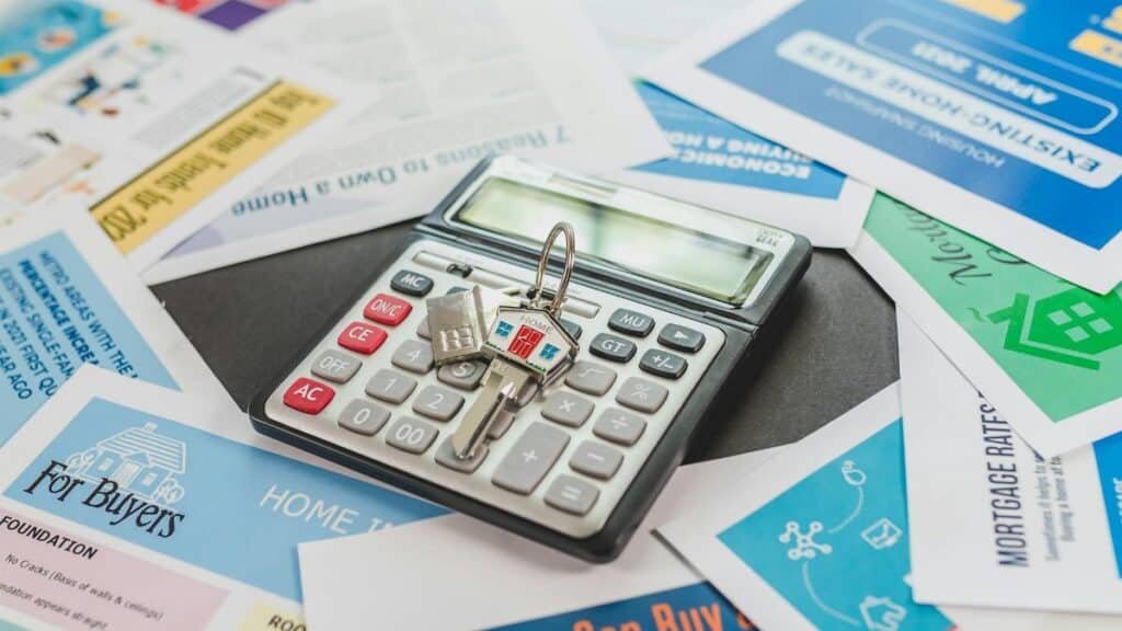 A calculator and real estate flyers depicting financial planning for home buyers.