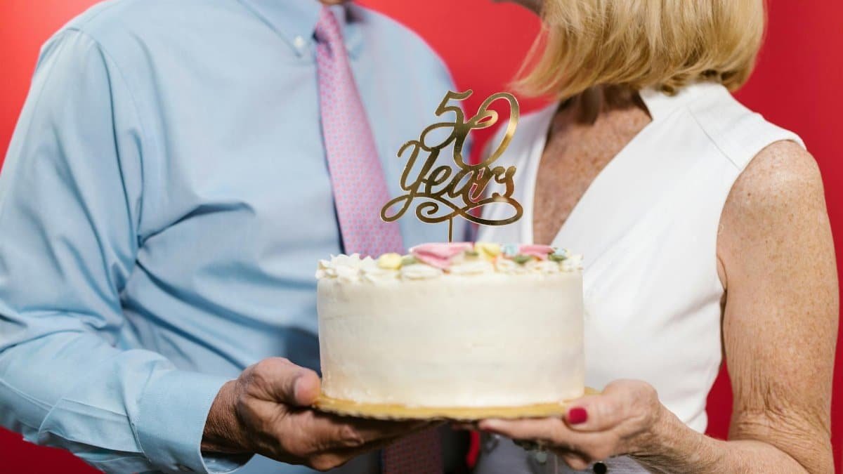 A couple celebrating their 50th anniversary with a decorative cake, symbolizing a lasting bond.