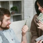 A cheerful couple managing their finances at home, holding cash and a receipt.