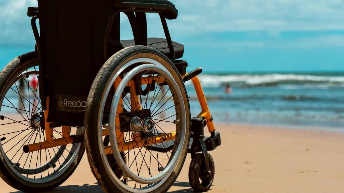 A vibrant beach scene featuring a wheelchair on the sandy shore with a view of the ocean waves.