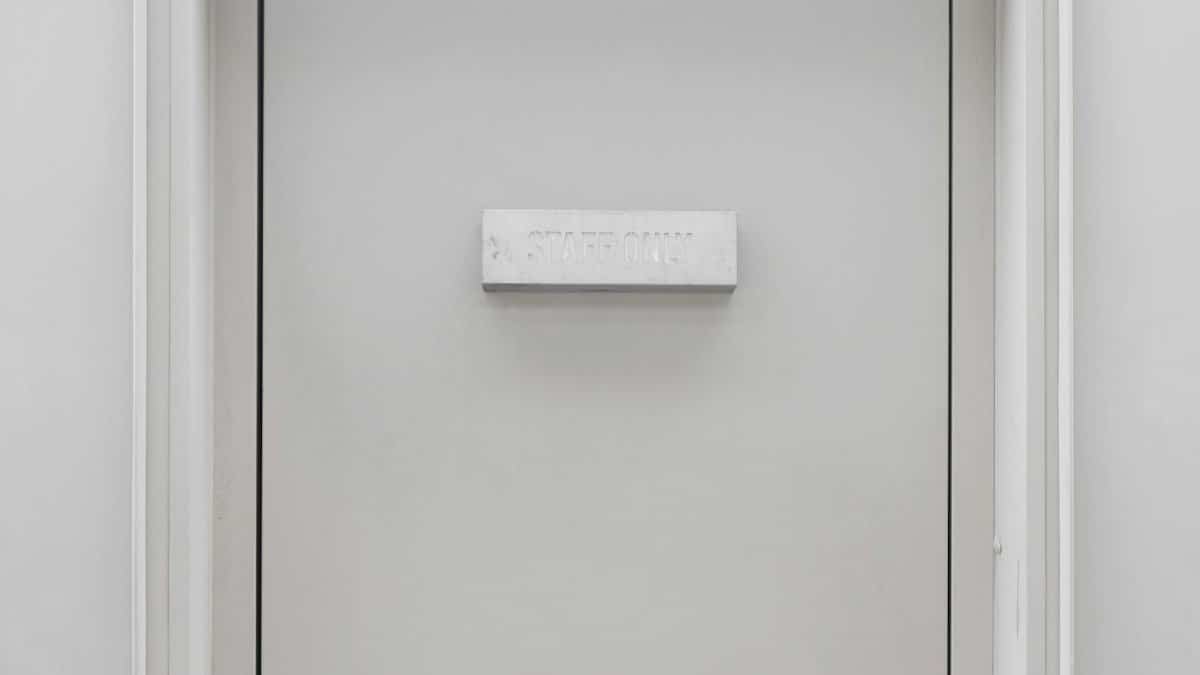 A minimalist white door with 'STAFF ONLY' signage, embodying simplicity and exclusivity.