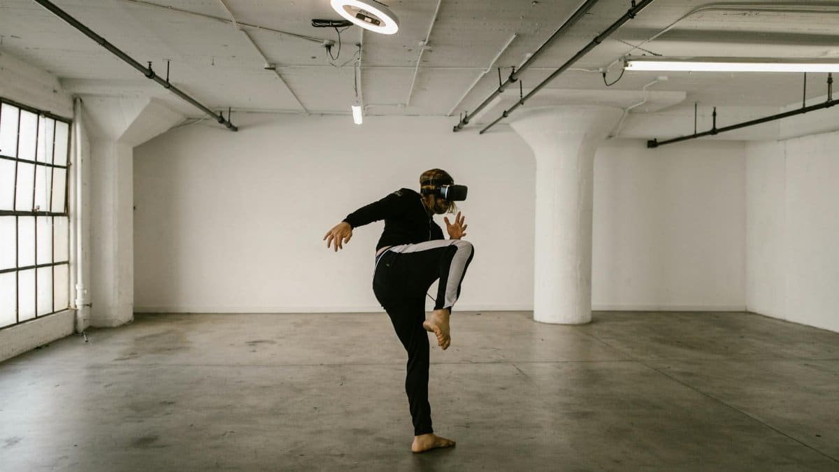 A man engaged in a virtual reality kickboxing session in an empty industrial loft space, wearing VR goggles.