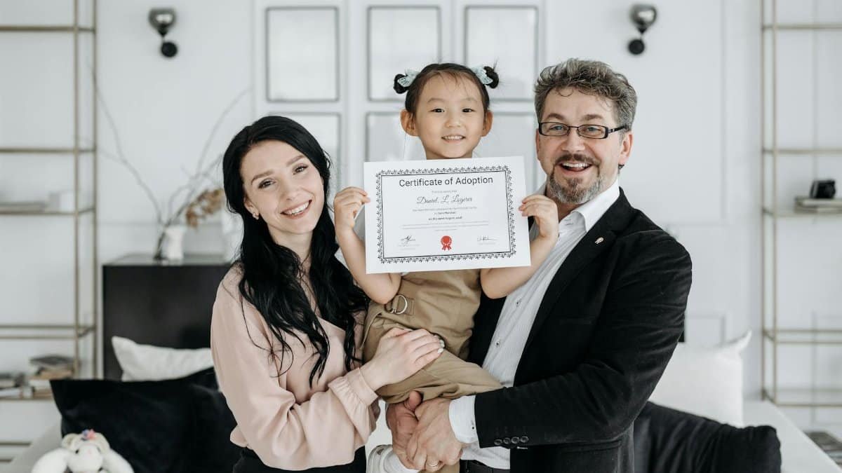 Happy multicultural family celebrating adoption with certificate indoors.