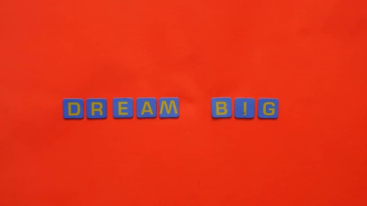 Blue tiles forming the 'Dream Big' quote against a striking red background.
