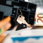 Keys with a house model, Euro bills, and charts suggesting real estate and financial themes.