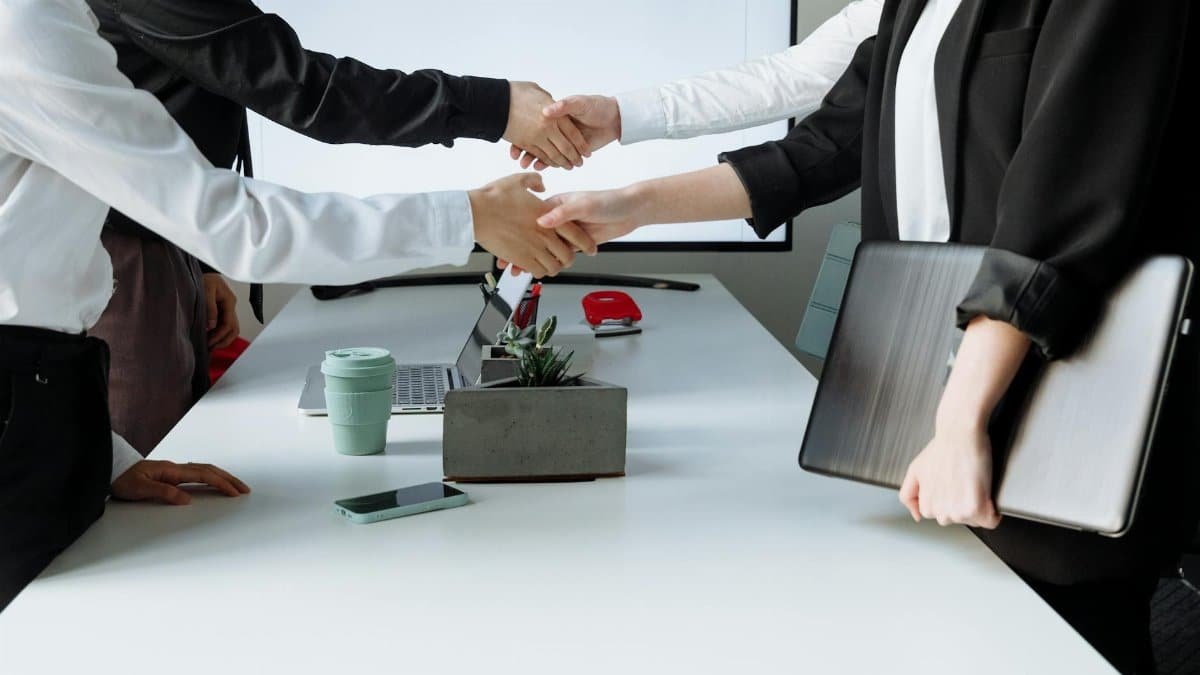 Professionals sealing a deal with a handshake across a conference table during a business meeting.