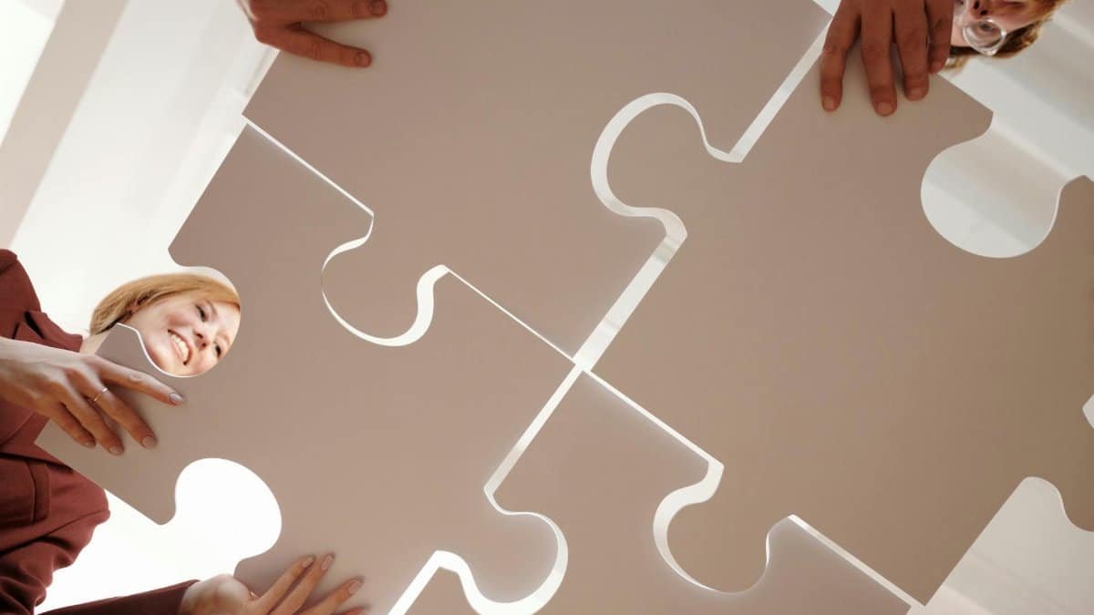 Low angle view of diverse team assembling large puzzle pieces, symbolizing unity and cooperation.
