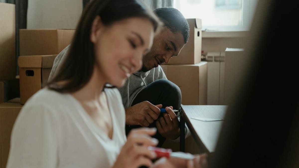 A happy couple assembling furniture in their new apartment surrounded by moving boxes.