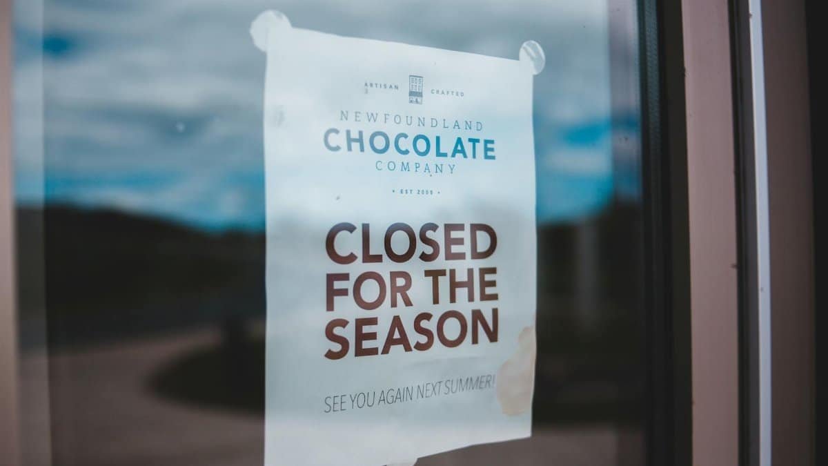 Announcement on white paper with CLOSED FOR THE SEASON inscription attached to glass surface at daytime