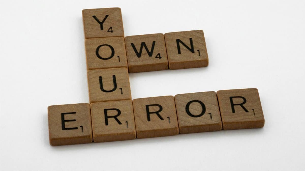 Scrabble tiles spelling 'Own Your Error' on a white background.