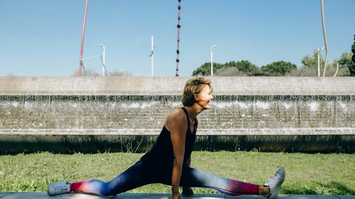 Woman in activewear doing a split outdoors, enjoying a healthy lifestyle.