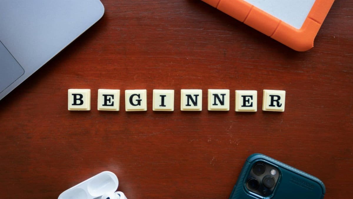 A top view of beginner workspace items including gadgets and letter dice on a wooden desk.