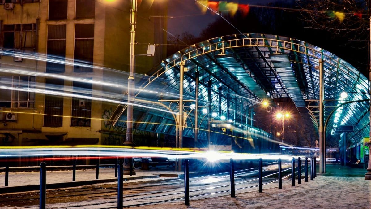 Vivid light trails at a tram station in Lviv, Ukraine captured at night in a dynamic urban scene.