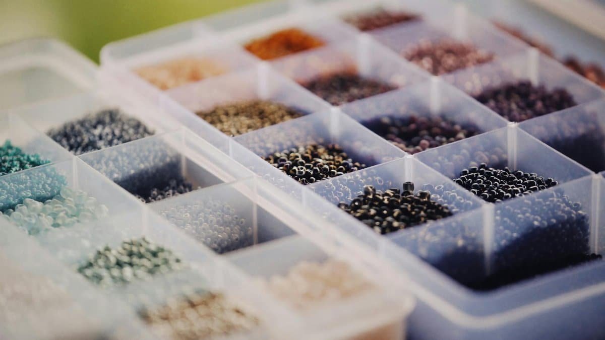 Vibrant beads sorted by color in a plastic container, perfect for crafting and jewelry making.