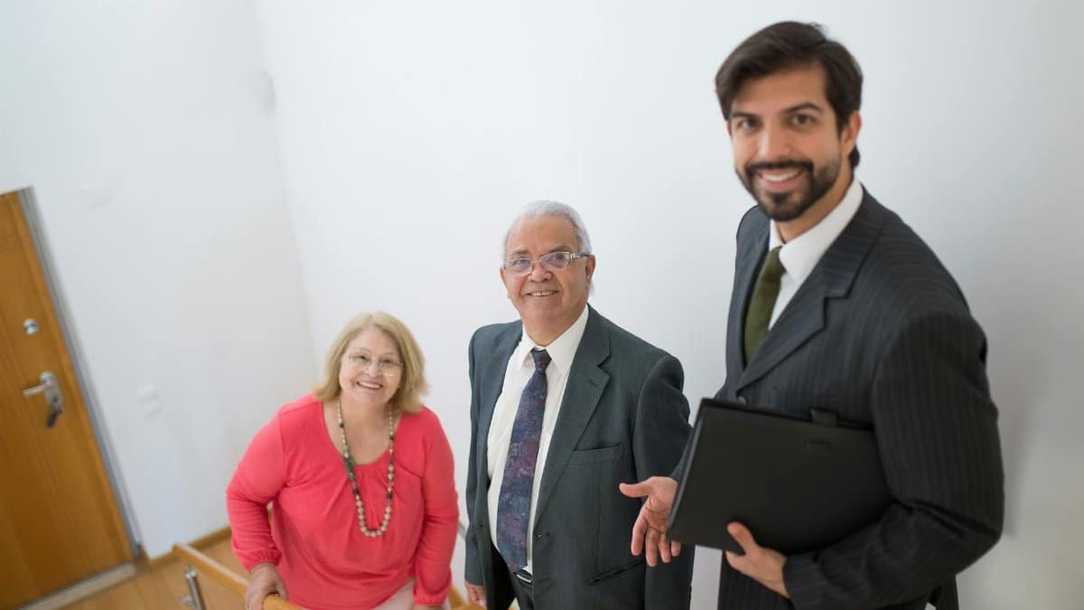 Realtor assists senior couple in a modern home setting. Ideal for real estate themes.