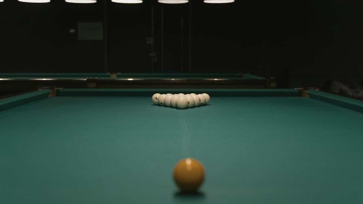 Classic billiards table setup with cue ball aimed for a perfect break in a dimly lit room.
