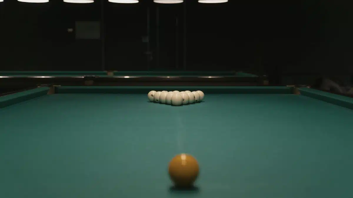 Classic billiards table setup with cue ball aimed for a perfect break in a dimly lit room.