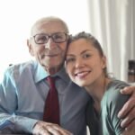 A joyful elderly man and young woman sharing an affectionate embrace indoors.