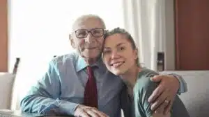 A joyful elderly man and young woman sharing an affectionate embrace indoors.