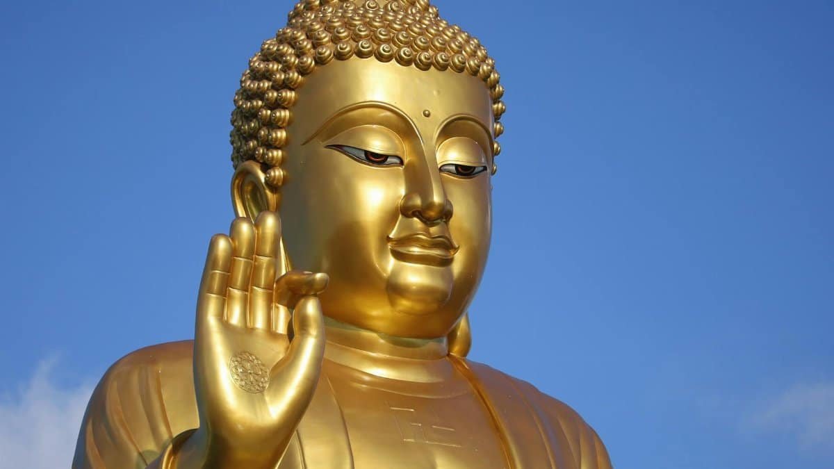 Golden Buddha statue against a bright blue sky, capturing serenity and spirituality.