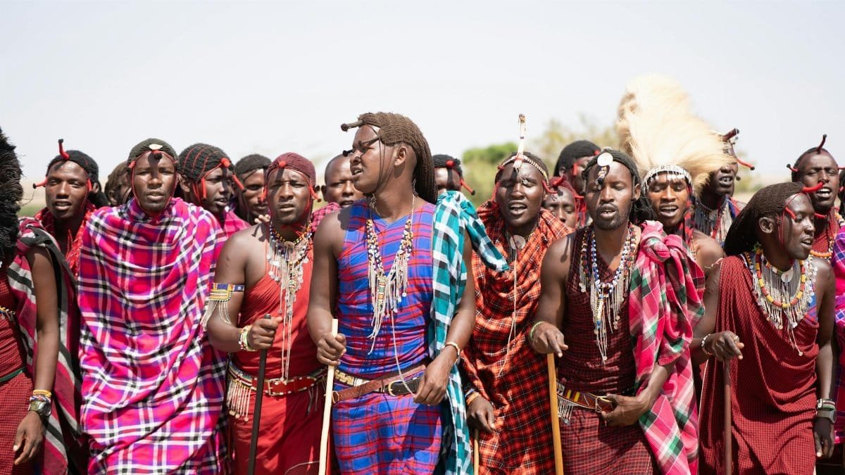 A group of Maasai tribe members dressed in traditional attire during a vibrant outdoor celebration in Kenya.