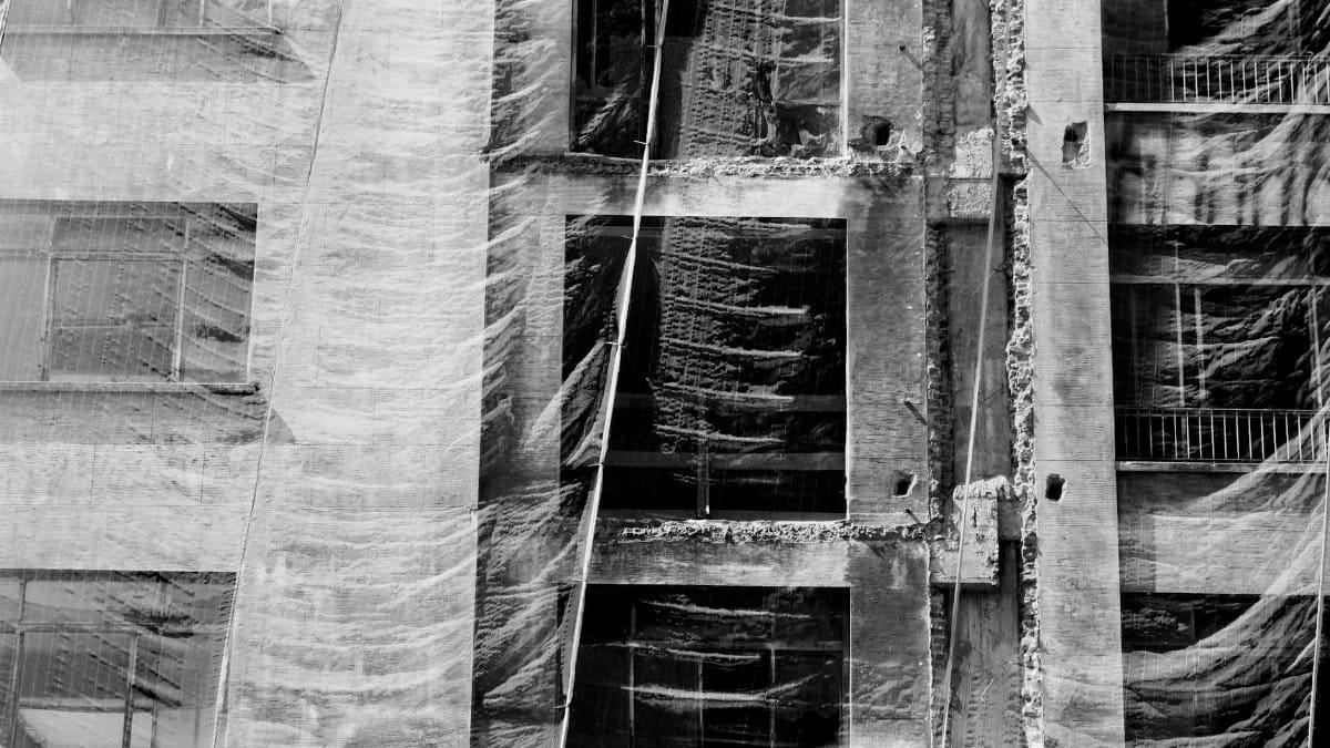 Abstract grayscale photo of a building facade covered with a mesh net during construction.